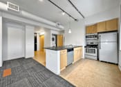 Thumbnail 16 of 50 - A kitchen with white appliances and wooden cabinets at The Des Moines Building Apartments, Iowa