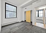 Thumbnail 18 of 50 - A room with a grey carpet and a wooden door at The Des Moines Building Apartments, Des Moines