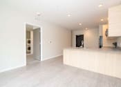 Thumbnail 3 of 26 - a white kitchen with a large island and a door to a laundry room at Rowat Lofts, Des Moines Iowa   