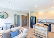 Thumbnail 1 of 26 - a living room with a couch and a kitchen at Rowat Lofts, Des Moines, 50309  