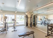 Thumbnail 20 of 26 - a gym with exercise equipment and a large window at Rowat Lofts, Des Moines, IA  