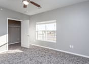 Thumbnail 8 of 32 - A room with a ceiling fan and a window overlooking a parking lot at The Barclay Apartments, Altoona, IA, 50009