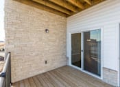 Thumbnail 6 of 32 - a balcony with a sliding glass door and a brick wall at The Barclay Apartments, Altoona, IA, 50009