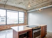 Thumbnail 29 of 39 - Kitchen with a brick wall and a large window at Clemens Building, Des Moines, IA