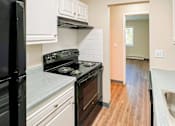 Thumbnail 11 of 19 - A kitchen with a black fridge, black stove, and white cabinets at The Hampton Meadows Apartments,Des Moines