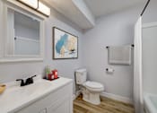 Thumbnail 5 of 19 - A white toilet sits in a bathroom next to a sink and a shower at The Hampton Meadows Apartments, Des Moines, IA