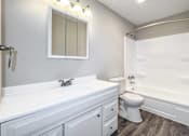 Thumbnail 21 of 21 - A white bathroom with a toilet, sink, and bathtub at The Ridges Apartments, Iowa