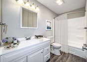 Thumbnail 2 of 21 - A white bathroom with a toilet, sink, and shower at The Ridges Apartments, Des Moines, IA