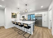Thumbnail 3 of 30 - a kitchen with a large island and a stainless steel refrigerator at Matilda 235 Townhomes, Des Moines, 50309