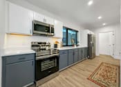 Thumbnail 8 of 30 - a kitchen with blue cabinets and a stove and a microwave at Matilda 235 Townhomes, Des Moines, IA