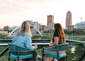 Thumbnail 9 of 53 - Two women sitting on a balcony overlooking a city skyline.at Level, Des Moines Iowa   