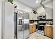 Thumbnail 25 of 53 - A modern kitchen with a stainless steel refrigerator and wooden cabinets.at Level, Des Moines, IA  