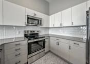 Thumbnail 31 of 53 - A kitchen with white cabinets and a black stove top oven.at Level, Des Moines  
