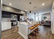 Thumbnail 17 of 34 - an open kitchen and living room with an island and bar stools at Linc, Des Moines, IA  