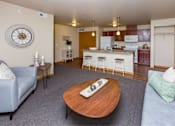 Thumbnail 4 of 35 - a living room with a couch and a table in front of a kitchen at Melbourne Apartments, Des Moines, IA,  50320