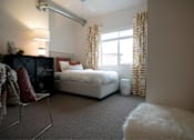 Thumbnail 6 of 35 - a bedroom with a bed and a window with curtains at Melbourne Apartments, Des Moines, IA