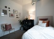 Thumbnail 8 of 35 - a bedroom with a bed and a lamp and pictures on the wall at Melbourne Apartments, Des Moines, Iowa