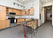 Thumbnail 1 of 42 - a kitchen with wooden cabinets and a table with stools at Eagle View Lofts, Des Moines, 50309