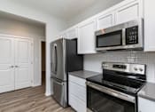 Thumbnail 4 of 21 - A kitchen with black appliances and white cabinets. at Two Rivers Home Rentals, West Des Moines, IA