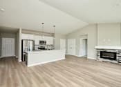 Thumbnail 10 of 21 - an empty living room with a kitchen and a fireplace at Two Rivers Home Rentals, Iowa