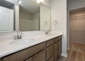 Thumbnail 19 of 21 - A bathroom with a sink, mirror, and wooden cabinets. at Two Rivers Home Rentals, Iowa 50266