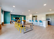 Thumbnail 23 of 28 - A modern kitchen with a bar and blue chairs.