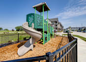 Thumbnail 19 of 28 - A playground with a green slide and a black fence.
