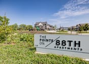 Thumbnail 27 of 28 - A sign for The Pointe on 88th Apartments in front of a building and some trees.