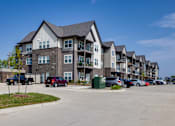 Thumbnail 21 of 28 - A row of townhouses with cars parked in front.