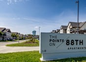 Thumbnail 28 of 28 - A sign for The Pointe on 88th Apartments in front of a grassy area and buildings.