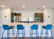 Thumbnail 13 of 28 - A kitchen with a white counter top and blue bar stools.