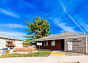 Thumbnail 47 of 90 - a small brick building with a fence and a tree in front of it at Rosemont Place Apartments, Des Moines, IA
