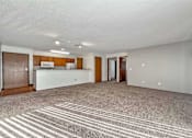 Thumbnail 8 of 40 - an empty living room with a kitchen and a rug at Autumn Park, Sioux Falls, SD  
