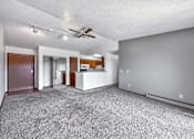 Thumbnail 32 of 40 - an empty living room with a ceiling fan and a kitchen at Autumn Park, Sioux Falls, SD  