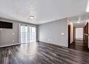 Thumbnail 5 of 40 - an empty living room with wood flooring and a sliding glass door at Autumn Park, South Dakota  