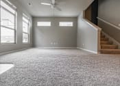 Thumbnail 2 of 37 - A spacious room with a carpeted floor and a staircase on the right side.