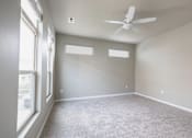 Thumbnail 8 of 37 - A room with a ceiling fan and carpeted floor.