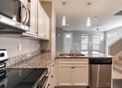 Thumbnail 4 of 37 - A kitchen with a granite countertop and stainless steel appliances.