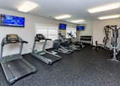 Thumbnail 33 of 50 - A gym with treadmills, elliptical machines, and exercise bikes.