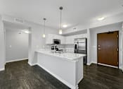 Thumbnail 25 of 50 - a white kitchen with a large island and a stainless steel refrigerator at Stonegate Crossing Apartments, Clive, IA, 50325