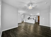 Thumbnail 24 of 50 - an empty living room with a ceiling fan and a kitchen at Stonegate Crossing Apartments, IOWA