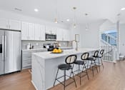 Thumbnail 2 of 77 - White kitchen island with pendant lighting and bar stools at The Flats at West Glen Apartments, West Des Moines, IA 50266