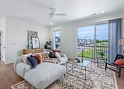 Thumbnail 3 of 77 - Modern living room with sectional and balcony view at The Flats at West Glen Apartments, West Des Moines, IA
