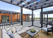 Thumbnail 5 of 77 - Outdoor patio with gray sectional and waterfront views at The Flats at West Glen Apartments, Iowa