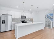 Thumbnail 72 of 77 - White kitchen island with marble countertop and pendant lights at The Flats at West Glen Apartments, West Des Moines, Iowa