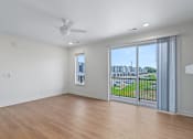 Thumbnail 67 of 77 - Empty living room with balcony and ceiling fan at The Flats at West Glen Apartments, West Des Moines