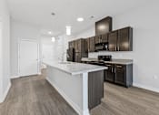 Thumbnail 2 of 52 - A modern kitchen with dark brown cabinets and a white island.