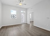 Thumbnail 27 of 52 - A room with a ceiling fan and wooden flooring.