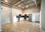 Thumbnail 15 of 40 - an empty kitchen with a wood floor and white cabinets and stainless steel appliances at Velocity Apartments, Iowa, 50309