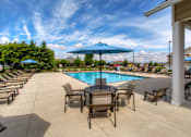 Thumbnail 7 of 15 - a swimming pool with a table and chairs under an umbrella at The Winhall of Williams Pointe Apartments, IOWA